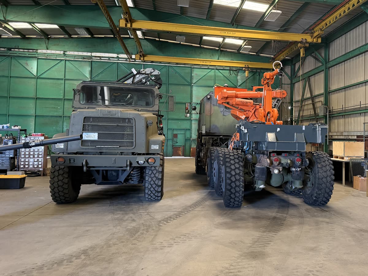 The M1070 HET and the COPMA knuckle-boom crane truck inside our Los Angeles workshop, under overhead gantry cranes
